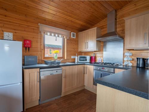a kitchen with wooden cabinets and a white refrigerator at Chalet Loch Leven Lodge 12 by Interhome in Kinross