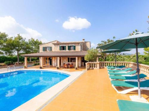 a house with a swimming pool with chairs and an umbrella at Villa Ca na Fideu by Interhome in Alcudia