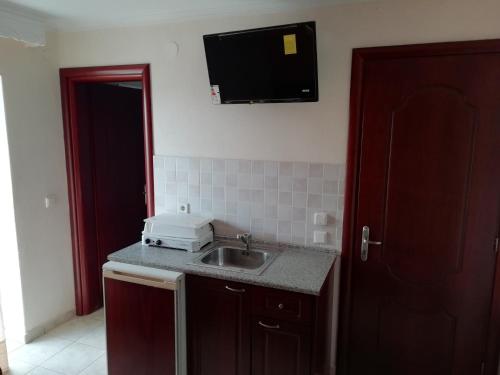 a kitchen with a sink and a television on the wall at Hotel Manos in Paralia Katerinis