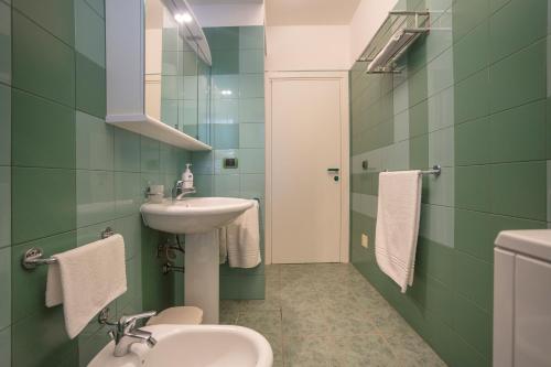 a green bathroom with a sink and a toilet at Terrazza Montalbano in Punta Secca