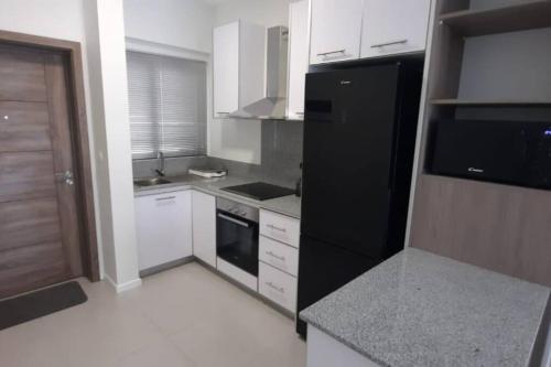 a kitchen with a black refrigerator and white cabinets at 2 Bedroom Apartment close to all amenities in Highlands