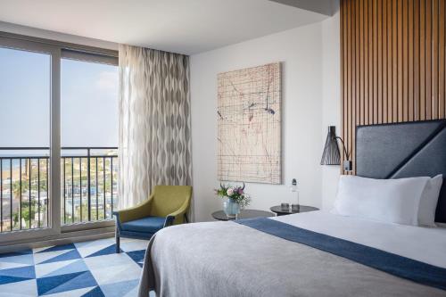 a hotel room with a bed and a chair and a window at Dan Accadia Herzliya Hotel in Herzliya