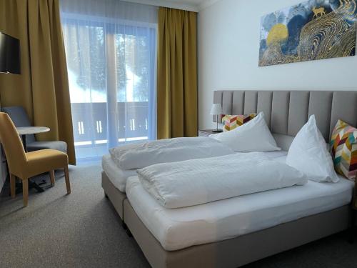 a bedroom with a large white bed and a window at Hotel HAAS in Bad Gastein