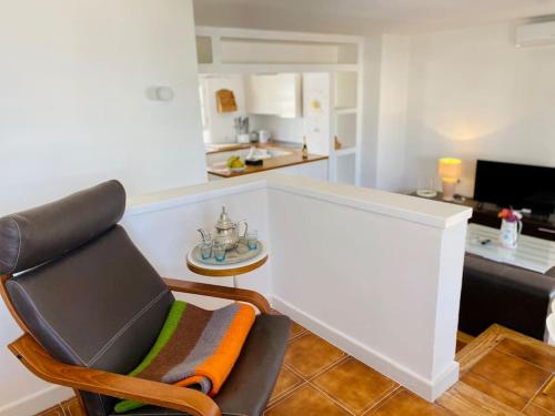 a living room with a chair and a kitchen at Villa muy cerca de la Playa. in Tías