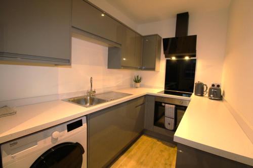 a small kitchen with a sink and a stove at No 10 @Short Stays in Basingstoke