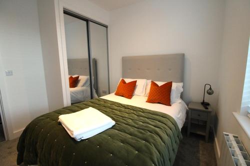 um quarto com uma cama grande e almofadas laranja em No 10 @Short Stays em Basingstoke
