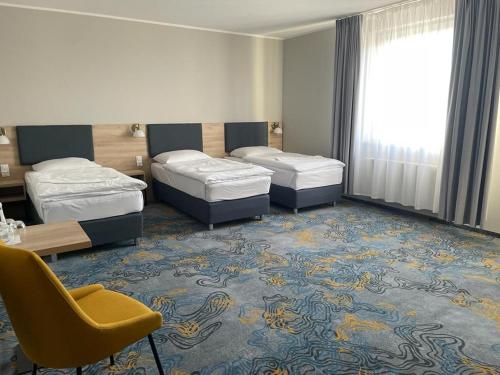 a hotel room with two beds and a chair at Hotel Dobosz in Police