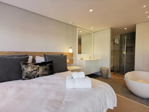 a bedroom with a large white bed and a tub at Betty in Plettenberg Bay