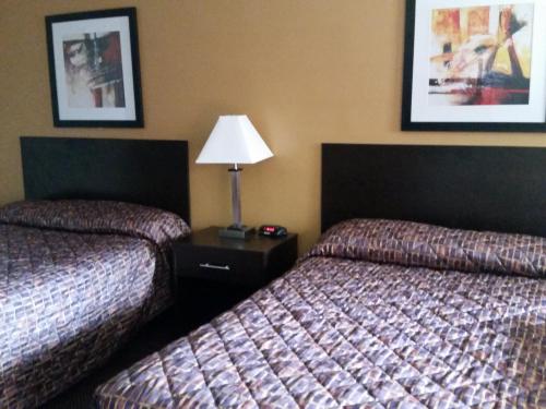 a hotel room with two beds and a lamp at German Village Inn Motel in Columbus