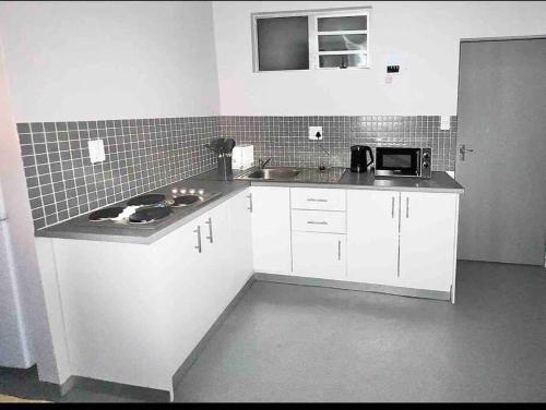 a kitchen with white cabinets and a counter top at Cosy Apartment next to Maboneng in Johannesburg