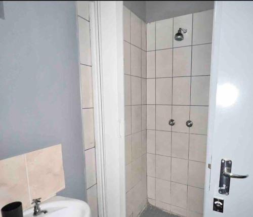 a bathroom with a shower with a toilet and a sink at Cosy Apartment next to Maboneng in Johannesburg