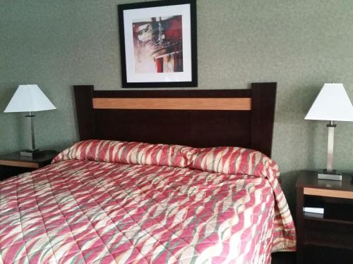 a bedroom with a bed and two nightstands and two lamps at German Village Inn Motel in Columbus