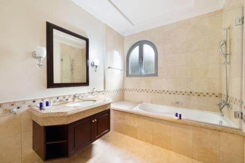 ein Badezimmer mit einer Badewanne, einem Waschbecken und einem Spiegel in der Unterkunft Maison Privee - Private Pool & Beach Access Villa with Cinematic Vws in Dubai