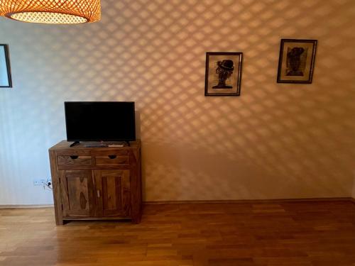 un televisor en un armario de madera con tres cuadros en la pared en THE PRAVETS PENTHOUSE en Pravets