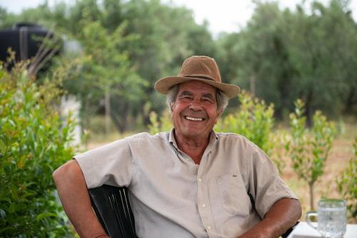 an older man wearing a hat sitting at a table at Agrikia tis Vasilikis in Ormília
