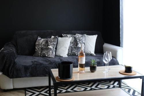 - un canapé avec des oreillers et une bouteille de vin sur une table dans l'établissement L'antichambre, neuf avec jardin à 100m de la mer, à Donville-les-Bains