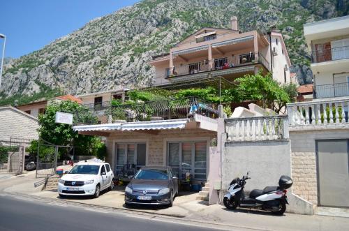 a house with a motorcycle and a car parked on a street at Apartments Kaludjerovic in Kotor