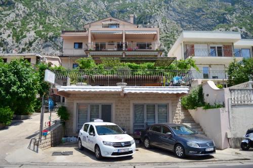 twee auto's geparkeerd voor een huis bij Apartments Kaludjerovic in Kotor