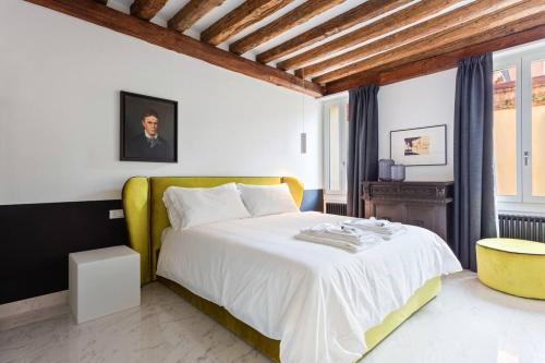 a bedroom with a large white bed with a yellow headboard at Dimora San Lorenzo Luxury Apartment in Venice