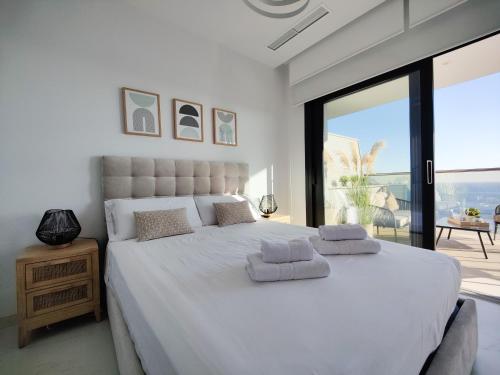 una camera da letto con un grande letto bianco con una grande finestra di SUNSET CLIFFS sea & sky apartments a Benidorm