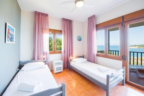 a bedroom with two beds and a balcony at Nereus & Oceanus Beachfront Apartments, Lagonisi Beach #FeelsLikeHome in Ormos Panagias