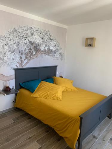 ein Schlafzimmer mit einem gelben Bett und einem Gemälde an der Wand in der Unterkunft Entre Ciel Et Nature in Venterol