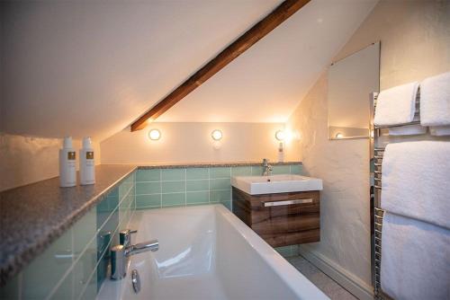ein Badezimmer mit einer weißen Badewanne und einem Waschbecken in der Unterkunft Gill Cottage, Castle Carrock, Nr Carlisle in Castle Carrock