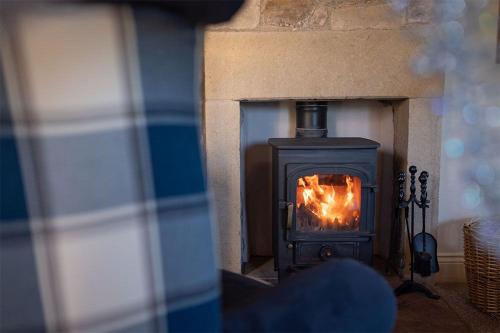 una chimenea con fuego en ella en Oak Cottage, Castle Carrock, Nr Carlisle en Castle Carrock