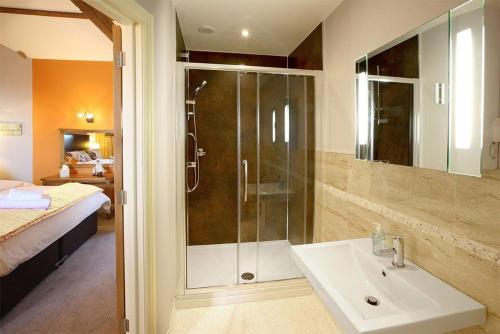 a bathroom with a shower and a sink and a bed at Oak Cottage, Castle Carrock, Nr Carlisle in Castle Carrock