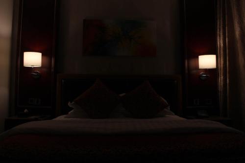 a bedroom with a bed with two lights on the wall at Velvet Hotel Jeddah in Jeddah