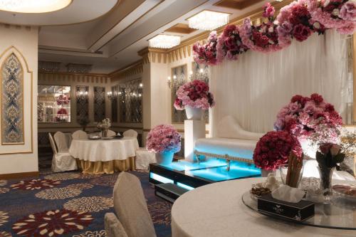 a lobby with tables and flowers in a room at Velvet Hotel Jeddah in Jeddah