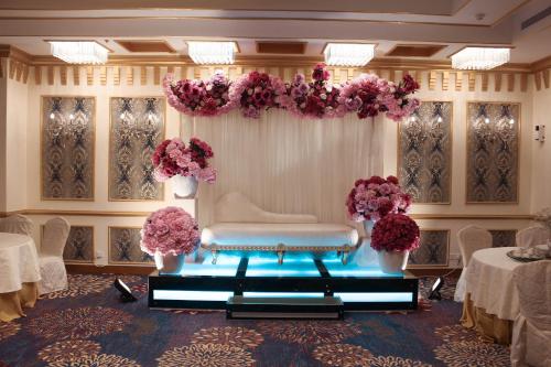 a room with a stage with flowers and a bench at Velvet Hotel Jeddah in Jeddah