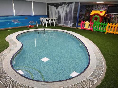 a large swimming pool with a playground and a table at Royal Tulip Apartments in Sharjah