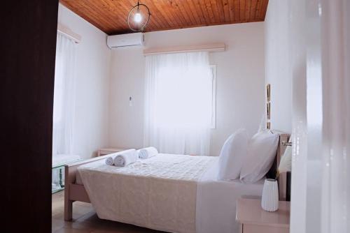 una camera da letto con un letto con lenzuola bianche e una finestra di The Homey a Sidari