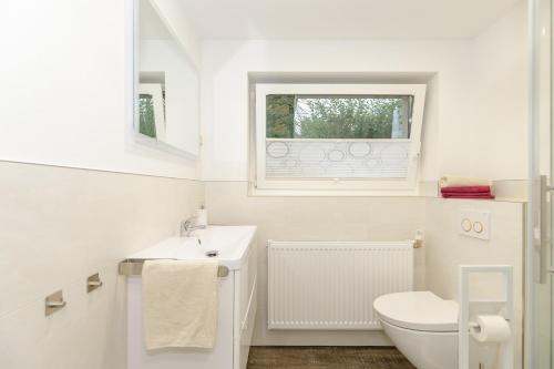 a white bathroom with a toilet and a window at Fewo Hafenblick in Kühlungsborn
