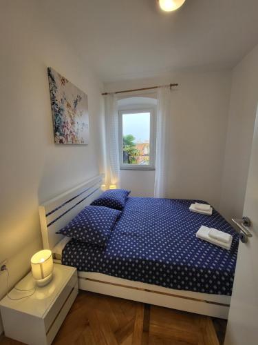 - une chambre avec un lit bleu et une fenêtre dans l'établissement Apartment Lucky, à Opatija