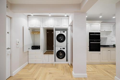 una cucina con mobili bianchi, lavatrice e asciugatrice di Bright House Cantemir a Bucarest