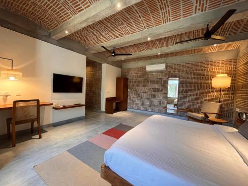 a bedroom with a bed and a desk and a tv at Ostel In in Puducherry