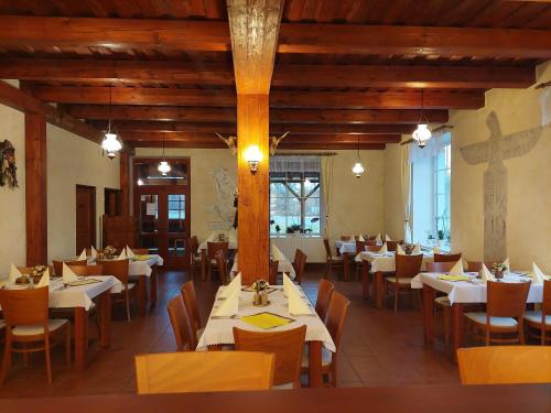 a restaurant with white tables and chairs and a cross on the wall at Penzion Country Steak Restaurant in Lanškroun