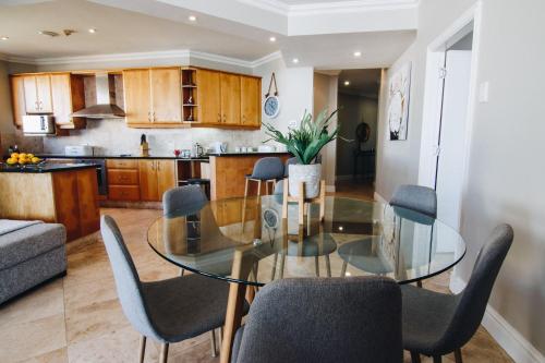 a dining room and kitchen with a glass table and chairs at 503 Oyster Schelles in Durban
