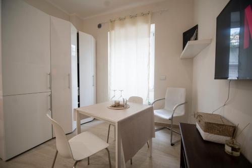 una sala da pranzo bianca con tavolo e sedie bianchi di Wi-Fi & NETFLIX - Luxe Suite nel Cuore di Salerno a Salerno