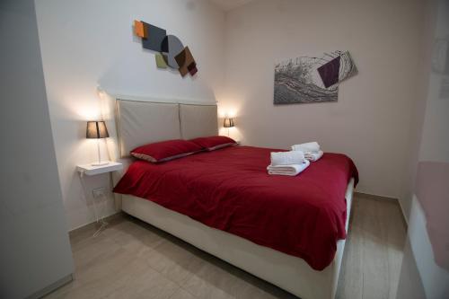 ein Schlafzimmer mit einem roten Bett mit zwei Handtüchern darauf in der Unterkunft Wi-Fi & NETFLIX - Luxe Suite nel Cuore di Salerno in Salerno