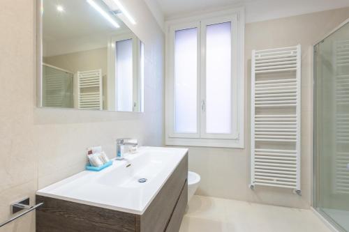 a white bathroom with a sink and a mirror at Rialto Bridge Luxury apartment in Venice