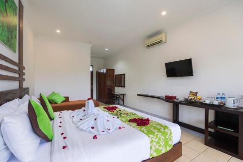 a bedroom with a white bed with flowers on it at Bali Wirasana Inn in Sanur