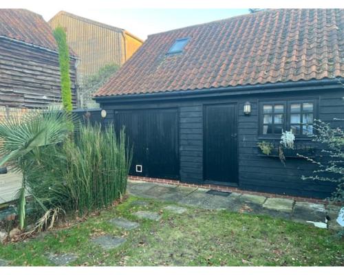 una pequeña casa negra con techo marrón en Two Storey Annex en Cottenham