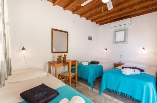 een kamer met 2 bedden, een bureau en een spiegel bij Pension Marias in Mykonos-stad
