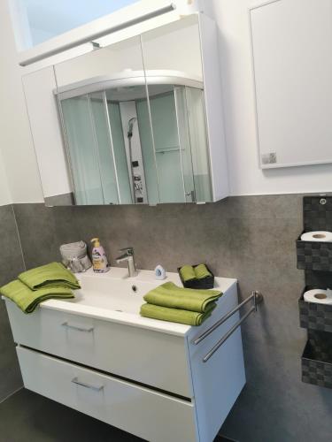 um lavatório de casa de banho com espelho e toalhas verdes em HomeW4 - Rosen Apartment em Hoheneich