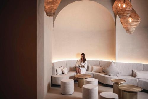 une femme assise sur un canapé dans une pièce avec ools dans l'établissement Biancaneve Family Hotel, à Selva di Val Gardena