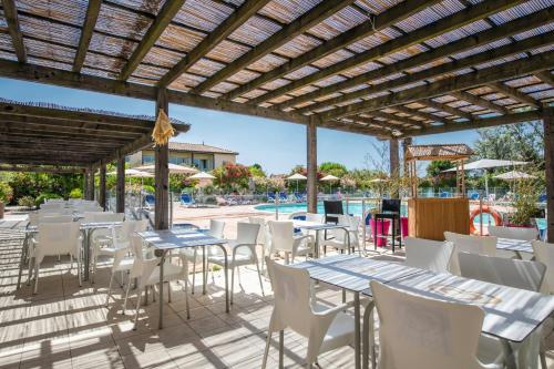 une terrasse avec des tables et des chaises ainsi qu'une piscine dans l'établissement SOWELL RESIDENCES Les Sablons, au Grau-du-Roi