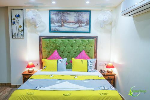 1 dormitorio con 1 cama con almohadas amarillas y rosas en Lime Tree Hotel Near 32nd Avenue Sector 29 Gurgaon en Gurgaon